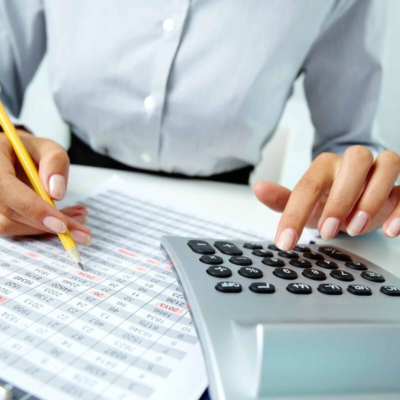 Photo of hands making notes with pencil and pressing calculator buttons